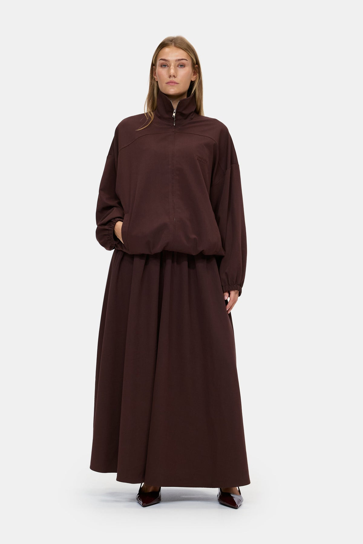 The Sculpted Jacket in Chocolate Brown, front, worn with the Sculpted Maxi Skirt