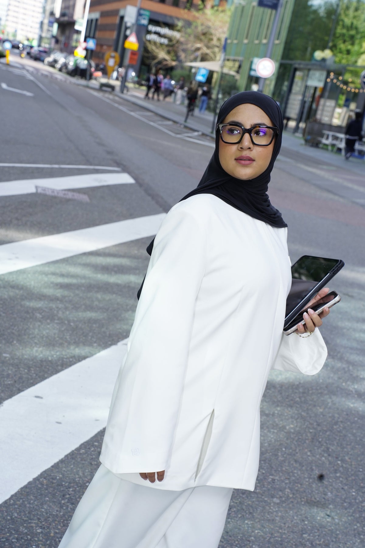 Model wearing the Structured Top in white with the Structured Trousers, seen from behind while crossing the street